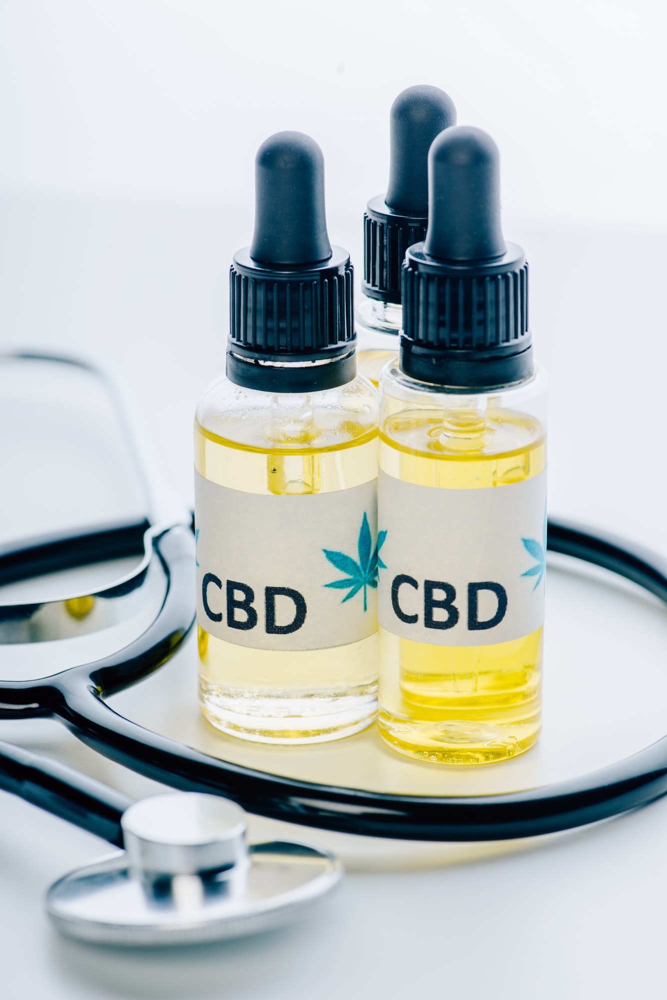 cannabis oil in bottles with lettering cbd and stethoscope on white background